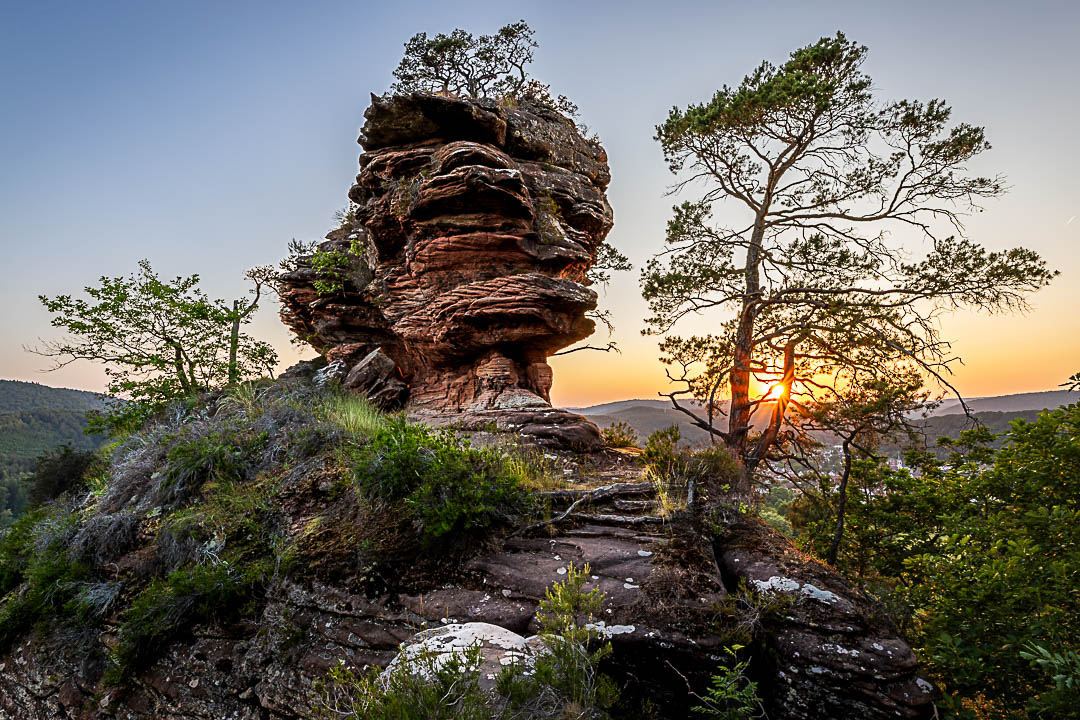 Sonnenuntergang am Hochstein mit Sonnenstern. Der Sandstein scheint eine Fratze zu sein