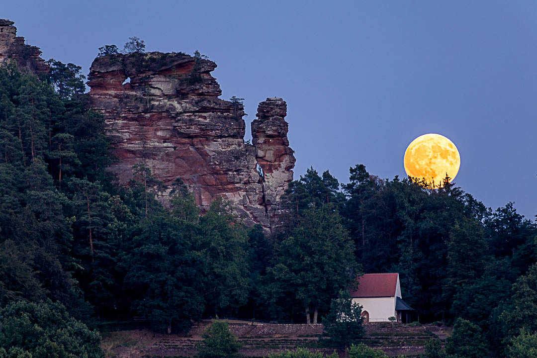 Vollmond am Hochstein. Der orangene Mond steht über der Kapelle des Soldatenfriedhofes