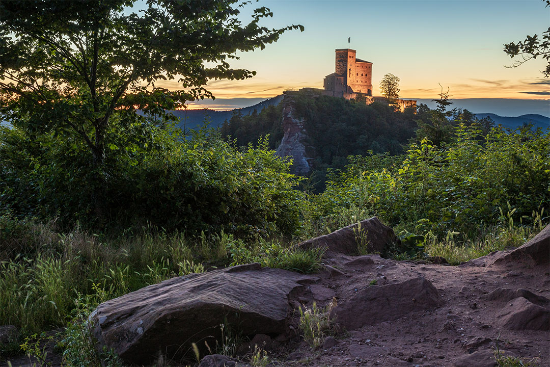 Sommerabend an der Burg Trifels bei Annweiler in der Pflaz, Im Pfälzerwald mit Sandsteinen. Die Burg ist beleuchtet